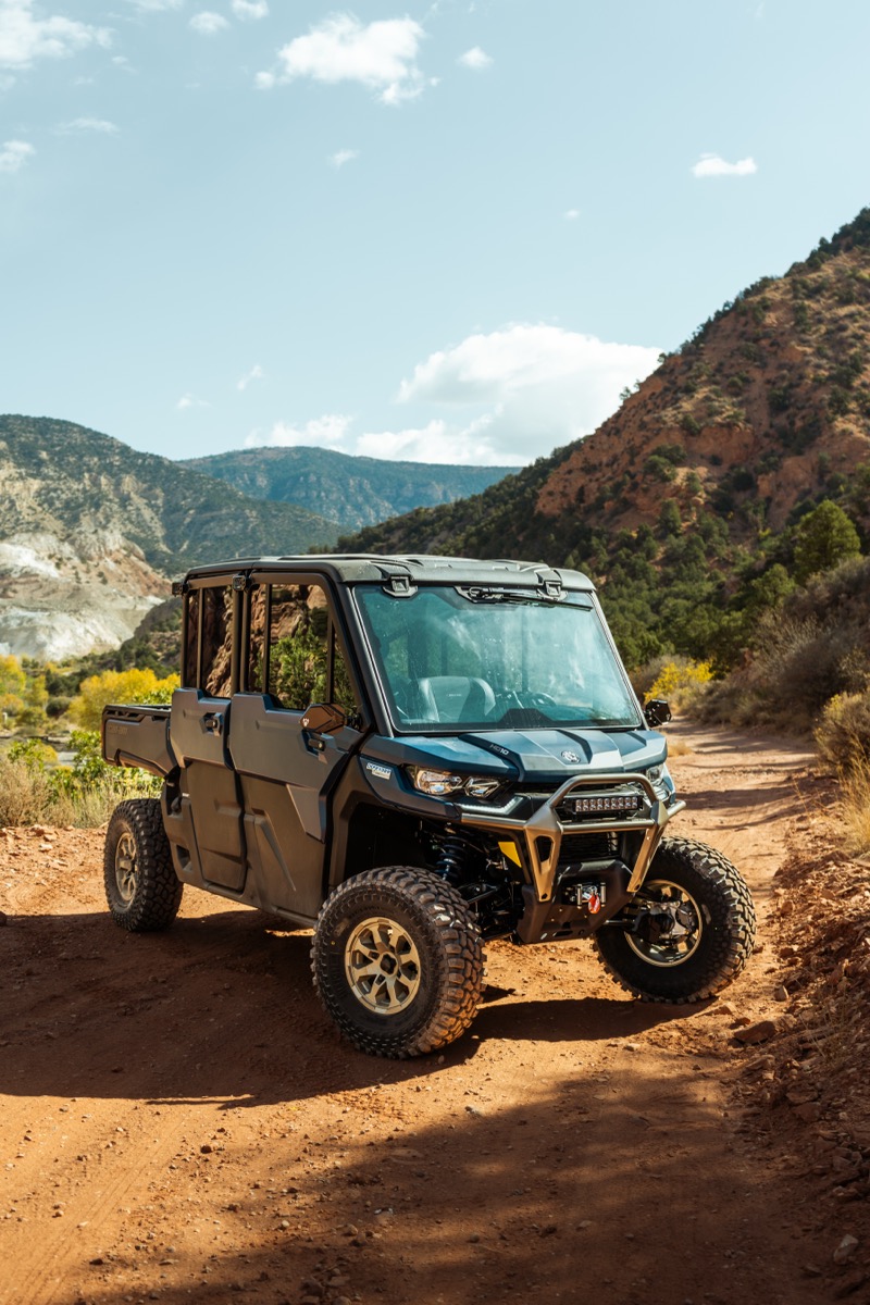 Can-Am Defender navigating a red rock canyon trail near Cedar City Utah with mountain scenery