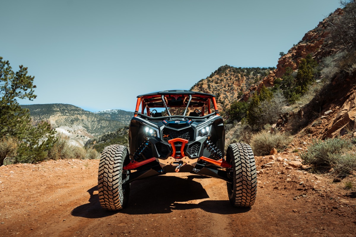 Can-Am Maverick X3 front view on a red rock trail in Southern Utah mountains showing aggressive sport suspension and stance