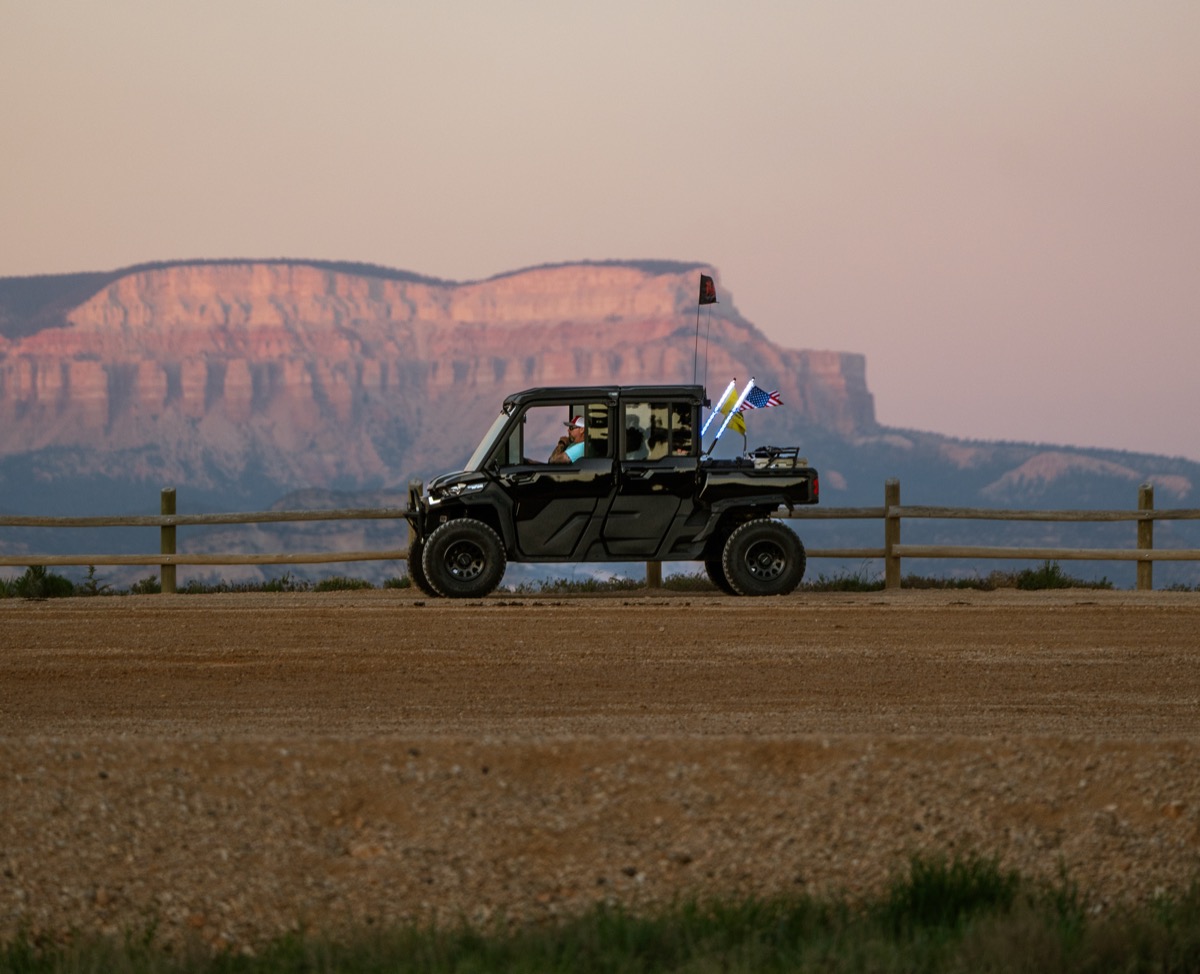 Can-Am side-by-side parked at golden hour with Southern Utah red cliff backdrop and American flag
