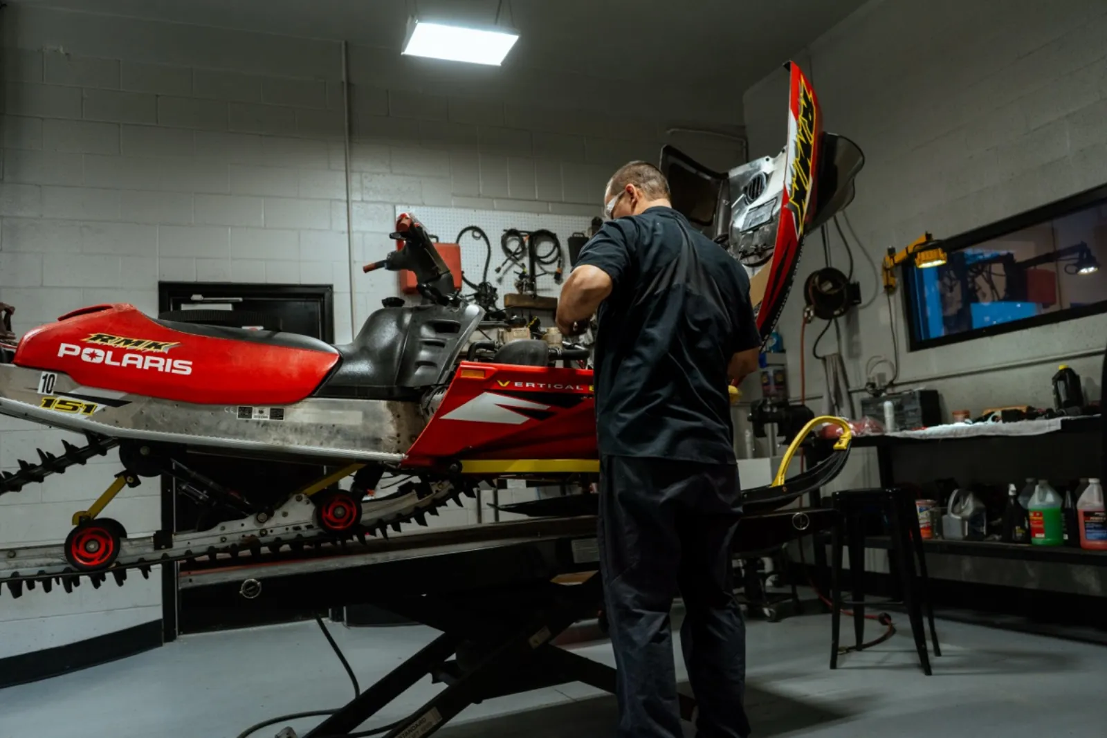 Technician servicing Polaris snowmobile at D&P Performance shop in Cedar City Utah
