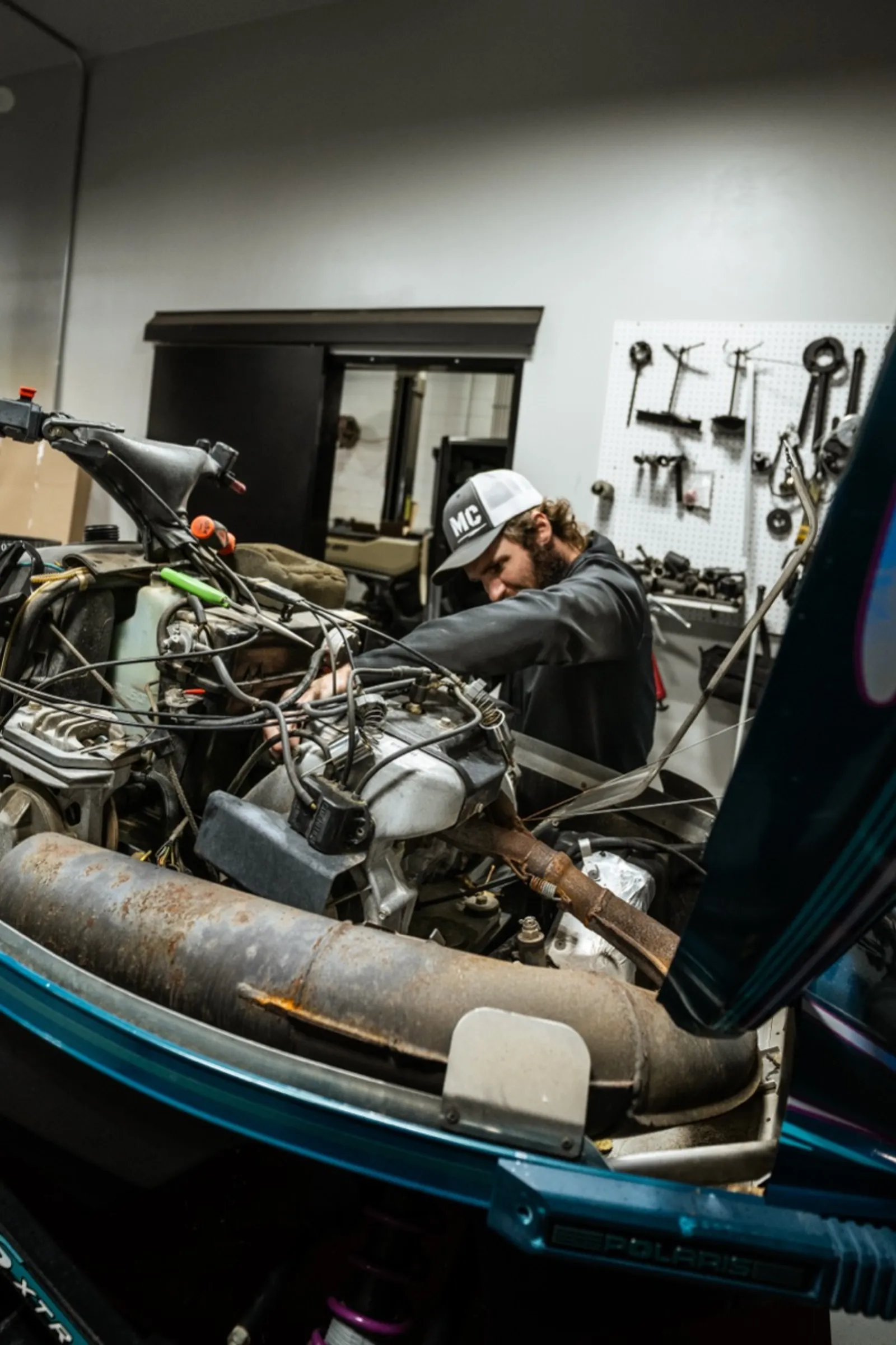 Technician inspecting engine wiring and electrical harness during powersports service in Cedar City